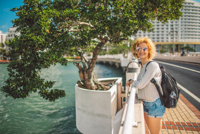 Portrait of smiling young woman standing against trees