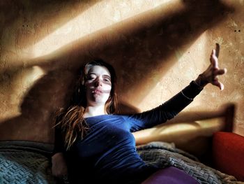 Portrait of serious young woman lying on bed at home