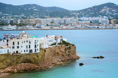 Panoramic view of sea and townscape against mountain