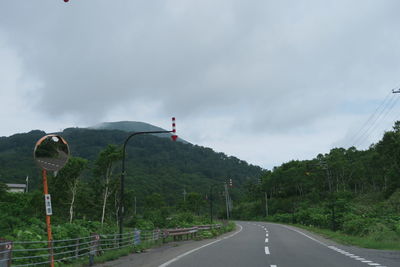 Road by trees against sky