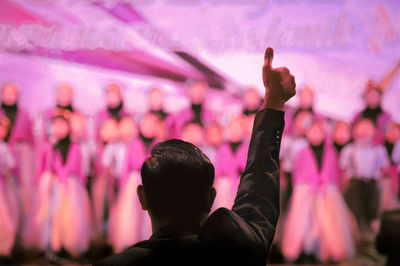 Rear view of man gesturing thumbs up during music concert