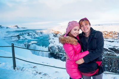 Portrait of smiling friends standing against gullfoss