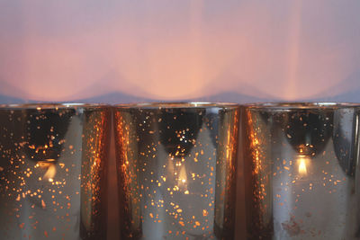 Close-up of lit tea light candle against wall