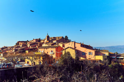 High angle view of houses by trees against clear blue sky