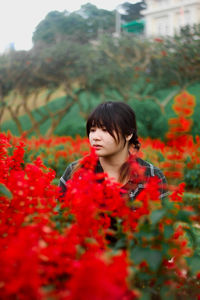 Portrait of young woman standing amidst yellow flowers