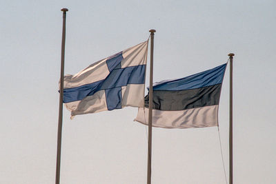 Low angle view of flags waving on pole against sky