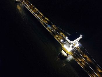 Illuminated bridge over river against sky at night