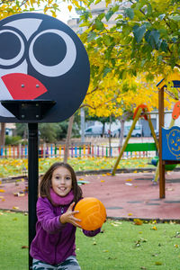 Portrait of smiling girl holding yellow ball at playground