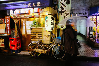 Rear view of woman walking on illuminated street at night