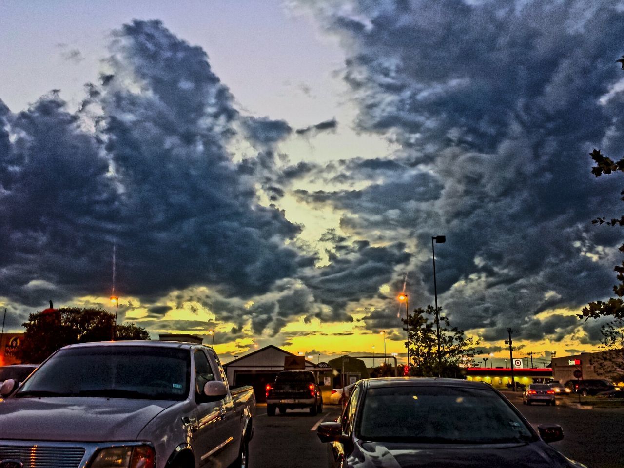 transportation, land vehicle, car, mode of transport, sky, cloud - sky, cloudy, street, weather, road, overcast, building exterior, cloud, sunset, dramatic sky, parking lot, dusk, outdoors, parking, on the move