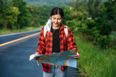 Young woman standing on road against plants