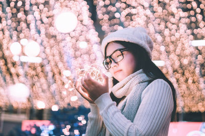 Young woman holding illuminated lights at night