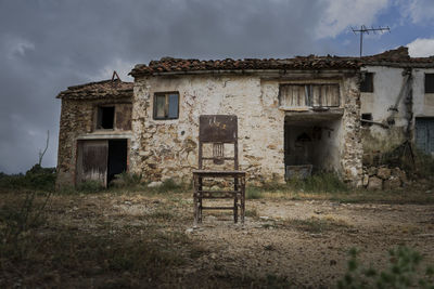 Old abandoned house in a abandoned village with a lonely chair in front of it in a cloudy day
