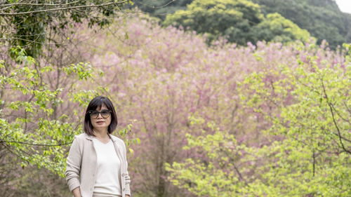 Portrait of smiling woman standing against plants