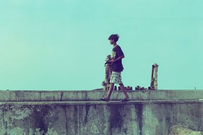 Side view of young man standing against wall