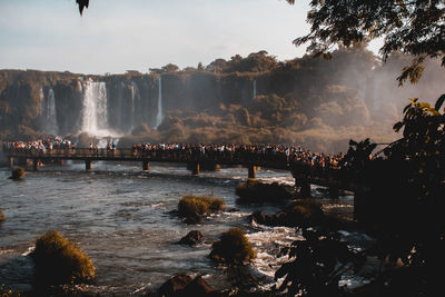 Crowd on pier over river at waterfall