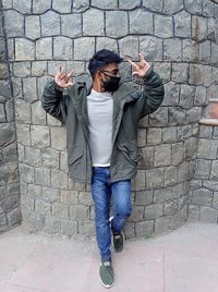 Full length of young man standing against wall