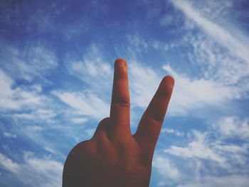 Low angle view of man gesturing peace sign against sky