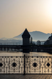 Scenic view of lake by buildings against sky during sunset