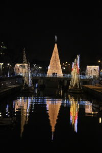 Illuminated bridge over river against sky at night