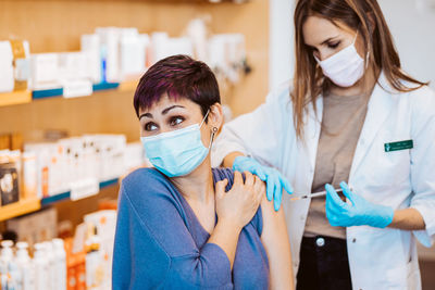 Portrait of young woman taking vaccine on arm