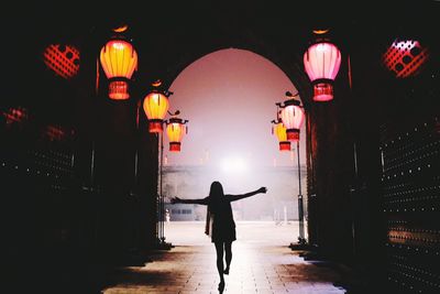 Rear view of woman walking on street at night