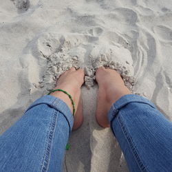 Low section of woman standing on sand