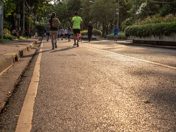 Rear view of people walking on road in city