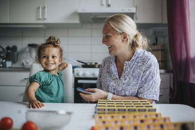 Happy girl playing game with mother at home