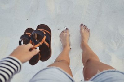 Low section of woman standing on sand at beach