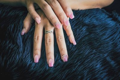 Cropped hands of woman with pink nail polish on rug