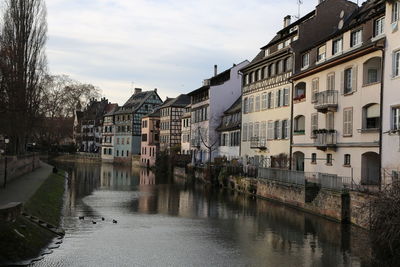 Houses by river in town against sky