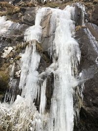 Icicles on rock against waterfall