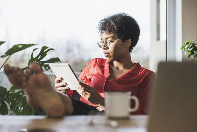 Young man using mobile phone while sitting on table