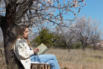 Young woman using laptop while sitting on tree