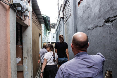 Rear view of people standing on alley amidst buildings in city