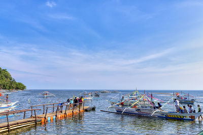 People on boats in sea against sky