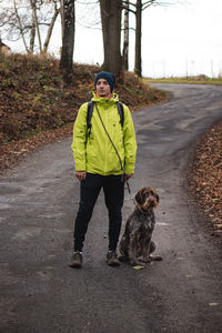Portrait of man with dog standing on road