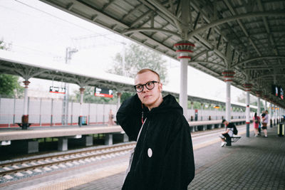 Young man looking away while standing at railroad station