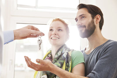 Young couple receiving house key from real estate agent