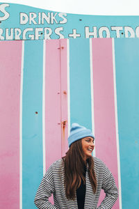 Young woman standing by striped wall