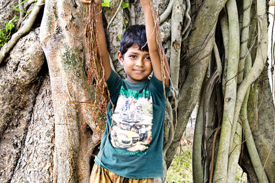 Portrait of boy standing on tree trunk