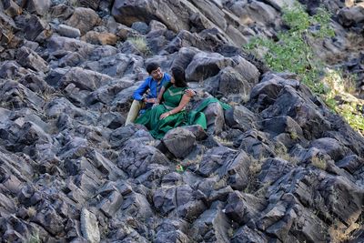 High angle view of man embracing woman while sitting on rock formation