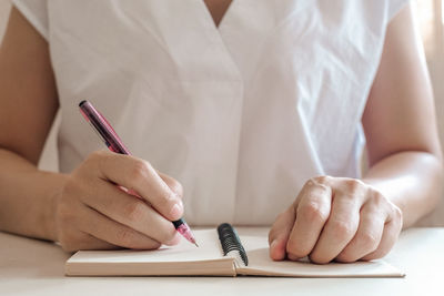 Midsection of woman reading book on table