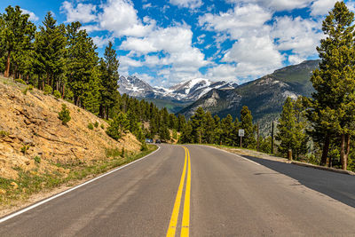 Road amidst trees and mountains against sky