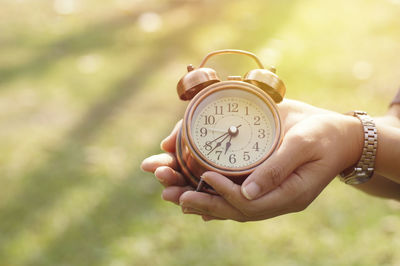 Close-up of hand holding alarm clock outdoors