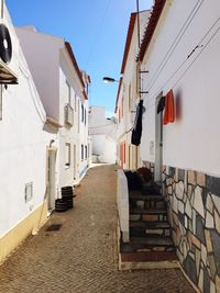 Walkway amidst buildings against clear sky