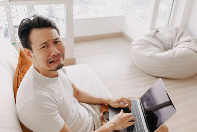 Portrait of depressed man using laptop at home