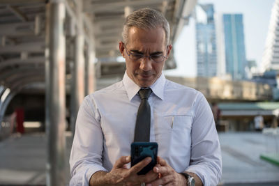 Businessman using mobile phone while standing outdoors