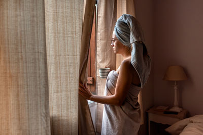 Side view of woman standing at home